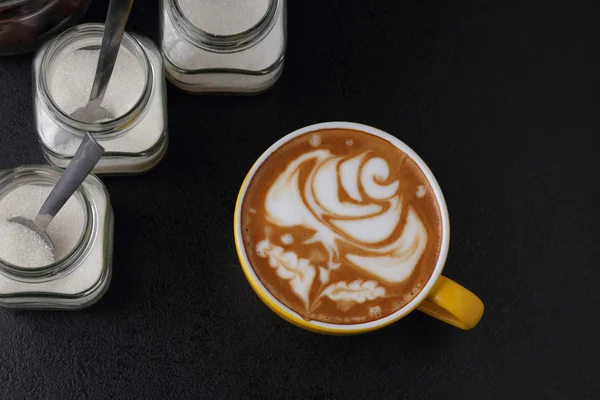 Kopp cappuccino och socker skålar på mörk bakgrund. Latte art. — Stockfoto