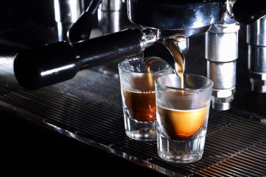 Espresso machine brewing a coffee. Coffee pouring into two shot glasses. Traditional Italian drink closeup with copy space. clipart
