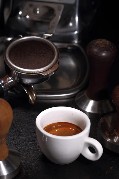 Witte porseleinen kopje koffie en portafilter van een espressomachine — Stockfoto