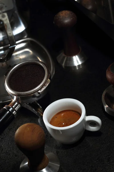 Witte porseleinen kopje koffie en portafilter van een espressomachine — Stockfoto