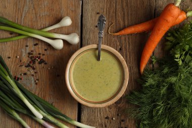 Bir seramik kase, havuç, soğan, sarımsak ve otlar içinde yeşil bezelye çorbası