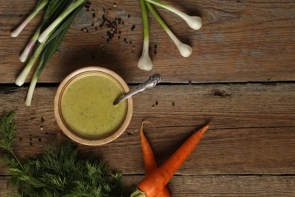 Sopa de ervilha verde em uma tigela de cerâmica, cenouras, cebola, alho e ervas — Fotografia de Stock