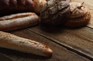 Ahşap arka plan üzerinde ekmek ürün yelpazesine sahip. Taze kopya alanı ile farklı tahıl çeşitli closeup ile pişirme