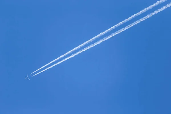 在蔚蓝的天空中 飞机飞得很高 两条白色冷凝道穿过空气空间 — 图库照片
