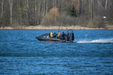 Hava motoru olan siyah bir cankurtaran botu gölde hızla yüzer. Baharın başlarında Belarus 'un kurtarıcılarının eğitimi.