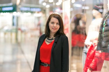 Kırmızı elbiseli ve siyah ceketli gülümseyen bir kadının portresi..