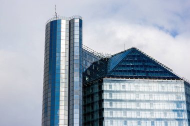 Bulutlu gökyüzüne karşı cam cepheli, büyük, güzel bir bina.