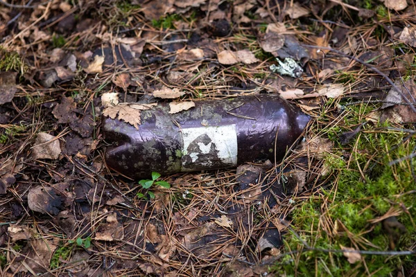 Discarded plastic trash in the forest. A plastic bottle left in the forest covered with leaves and needles.