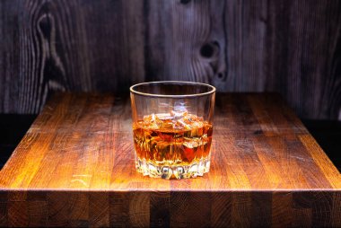 Meşe ağacının üstünde buz küpleri olan bir bardak viski..