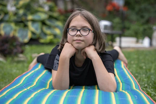 Nastoletnia Dziewczyna Okularach Leży Materacu Trawniku Letnim Ogrodzie Myśli Czymś — Zdjęcie stockowe