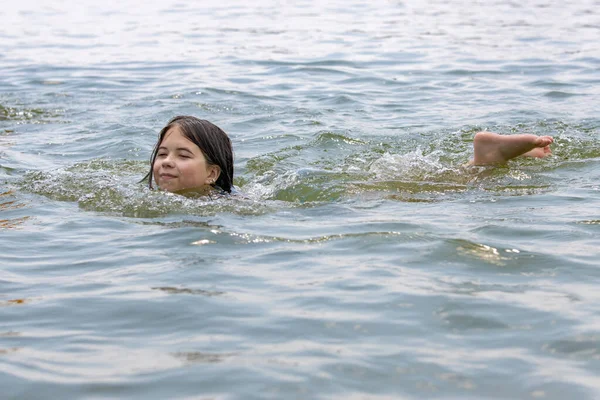 10代の女の子は美しい夏の天気で穏やかな暖かい海の水で泳ぐことを楽しんでいます ストックフォト