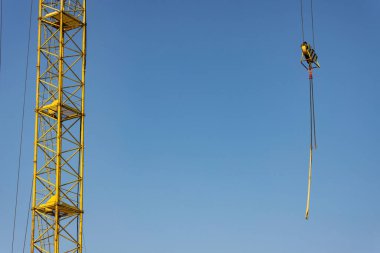 Açık mavi gökyüzü arka planına karşı uzun sarı kule inşaat vinci