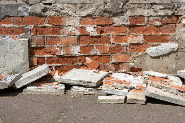 Collapsing facade of a brick house with a falling off decorative coating