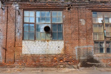 Büyük, harap olmuş pencereleri olan kırmızı ve beyaz tuğlalardan oluşan büyük, eski bir ev. Terk edilmiş eski bir fabrika..