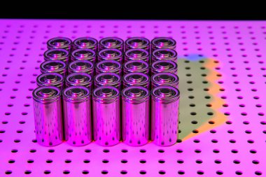 Yeni modern lityum iyonlu bataryalar ve artan kapasite. Ultraviyole lambayla aydınlatılmış bir laboratuvar masasındaki yeni pillerin prototipi..