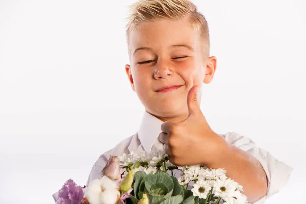 Alegre chico rubio de moda da ramo y pulgares hacia arriba en el fondo blanco del estudio, flores de entrega, Primavera de la Mujer Día —  Fotos de Stock