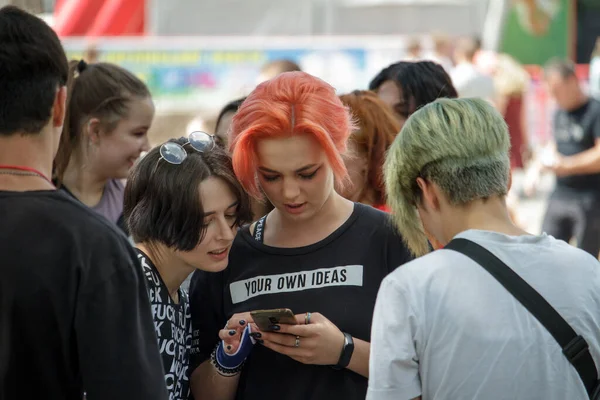 Firma nowoczesnej nieformalnej młodzieży na festiwalu, kilka dziewcząt korzysta z telefonu, młodzieży tłum w dużym mieście — Zdjęcie stockowe
