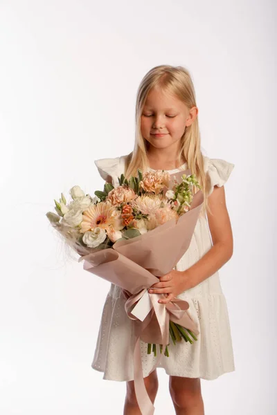 Retrato de estudio de linda chica rubia en vestido blanco con hermoso ramo de regalo, fondo blanco, enfoque selectivo Imagen de stock