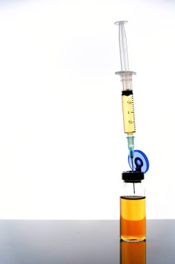 Tıbbi aşı dozajı ve şırınga ayna yüzeyinde, beyaz arka plan, seçici odak