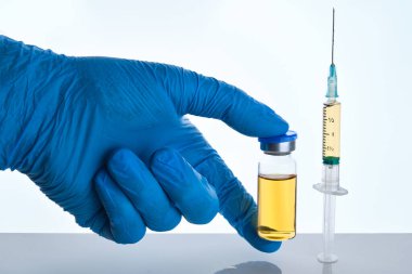 Mavi eldivenli erkek doktor elinde şırınga ve şişede covid-19 aşısı ilacıyla birden fazla doz enjekte ediliyor. Coronavirus tedavisi, grip ilacı aşı konsepti.