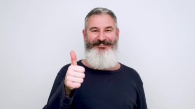 Neşeli, olgun bir adam el hareketi yapıyor ve mutlu bir yüzle kameraya bakıyor. Vücut dili ve mutlu insanlar konsepti.