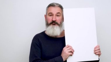 Beyaz tabelayı işaret eden neşeli sakallı adam, başparmaklar yukarı, seçimi onaylıyor, reklam konsepti, beyaz fon