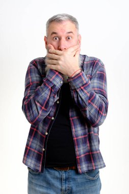 İki eliyle ağzını kapatırken sıradan kıyafetler giymiş yetişkin sakallı bir adamın stüdyo portresi. Bu inanılmaz bir şey. Anlatsana. Gerçekten mi? Öyle mi dersin?.