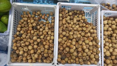 Langsat, lansium ya da Duku yığını pazarda beyaz bir sepet satışında. Market satmak için duku.ekran üst görünümü. Longkong meyveleri. Tayland meyveleri