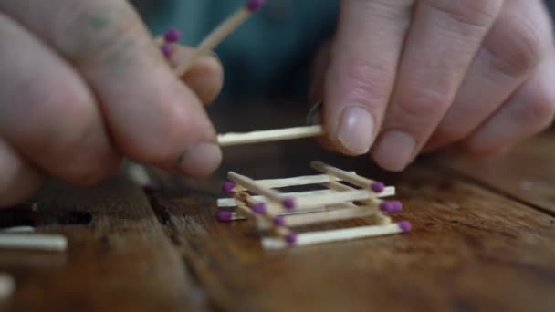 Una anciana construye una casa de fósforos — Vídeo de stock