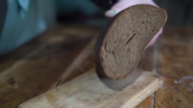 Kadın bıçakla siyah ekmek kesiyor.