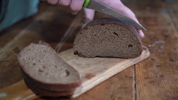 Vrouw snijdt zwart brood met een mes — Stockvideo