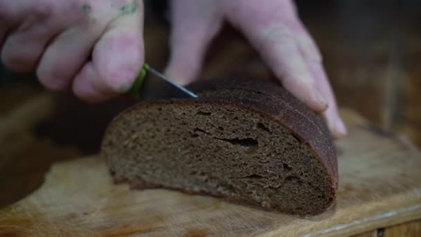 Kvinnan skär svart bröd med en kniv. Långsamma rörelser — Stockvideo