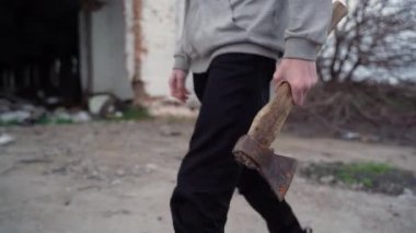 Genç, elinde baltayla eski yolda yürüyor.