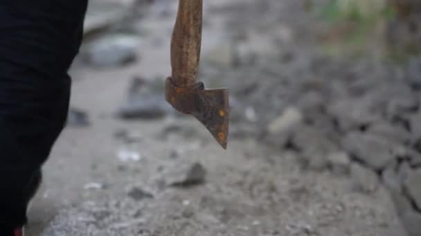 Ένας έφηβος περπατάει με ένα τσεκούρι μέσα στα ερείπια. — Αρχείο Βίντεο