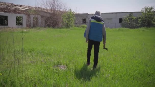 Un adolescent marche avec une hache sur une ferme abandonnée — Video