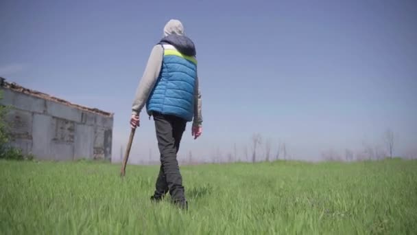 Um adolescente caminha com um machado em uma fazenda abandonada — Vídeo de Stock