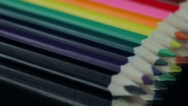 Crayons de couleur tournant sur une table noire . — Video