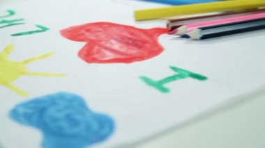 Çocuk boyalar beyaz kağıt üzerine çizer.