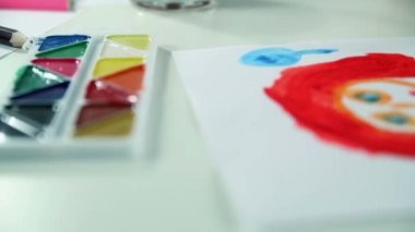 Çocuk boyalar beyaz kağıt üzerine çizer.