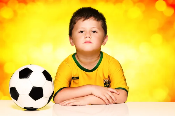 Poika brasilialaisessa kansallisessa jalkapallopaitassa ja pallossa — kuvapankkivalokuva