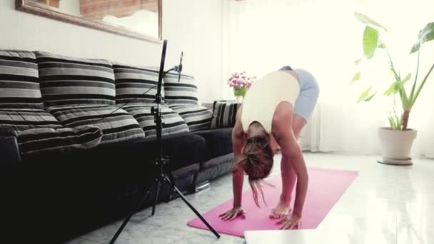 Entrenamiento en línea del instructor de yoga durante el bloqueo pandémico permanecer en casa. Mujer hispana joven que transmite en vivo entrenamiento con videollamada usando smartphone en su apartamento — Vídeos de Stock