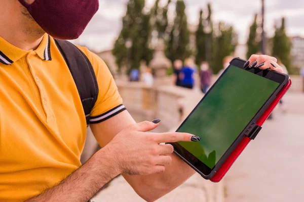 Der junge Mann aus Lateinamerika nutzt ein digitales Tablet. Soziale Distanz in einer neuen normalen Pandemie. Touchscreen mit Chroma-Taste — Stockfoto