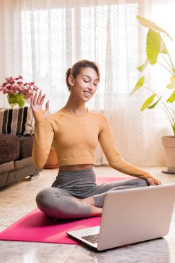 Kişisel antrenör, karantina sırasında evdeki sanal sınıf video konferansına dizüstü bilgisayarla giriyor. Genç İspanyol kadın yoga sınıfı.