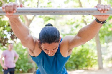 Genç adam barfiks çubuğunda jimnastik yapıyor. Güç ve kararlılık gösteriyor.