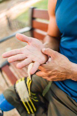 Engelli sporcu nasırlı elleri inceliyor, açık hava jimnastik eğitimi sırasında kendini adamış ve çaba gösteriyor.