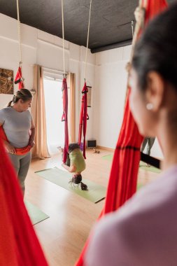 Havadaki vinyasa yoga sınıfına aktif olarak katılan bir grup kadın, hamakları ters çevirme egzersizleri ve sağIık için kullanıyorlar.