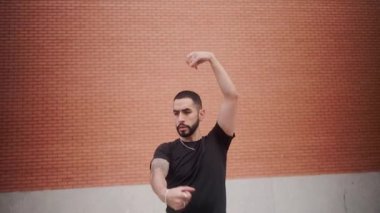 Dövmeleri olan yetenekli İspanyol bir adam İspanya 'da bir tuğla duvara karşı etkileyici ve tutkulu flamenko dansı yapıyor.