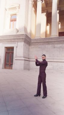 Genç İspanyol adam tutku ve zarafetle geleneksel flamenko dansı yapıyor. Seçkin bir sanatçı tarihi bir binanın önünde karmaşık adımlar atıyor.