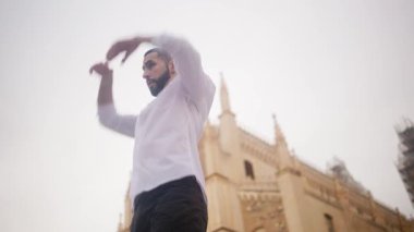 Tutkulu İspanyol dansçı sokaklarda geleneksel flamenko gösterisi yapıyor. Erkek sanatçı, arka planda bir katedral ile zarafet ve tutkuyla hareket ediyor.