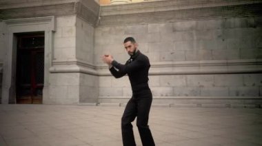 Tutkulu İspanyol adam etkileyici hareketlerle geleneksel flamenko dansı yapıyor. Profesyonel sanatçı bir İspanyol şehir meydanında gösteri yapıyor.